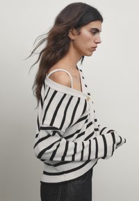 Black and white striped oversized sweater with a ribbed texture. Features a wide neckline and dropped shoulder design.