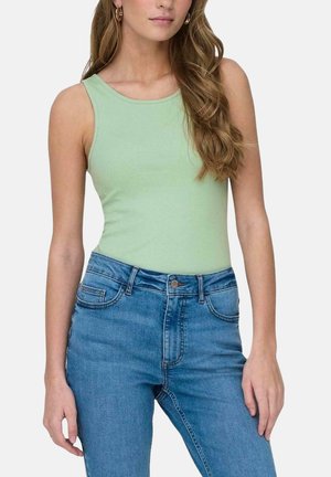Top de tirantes acanalado verde claro con escote redondo, combinado con jeans de mezclilla azul de cintura alta que cuentan con bolsillos frontales y cierre de botón.
