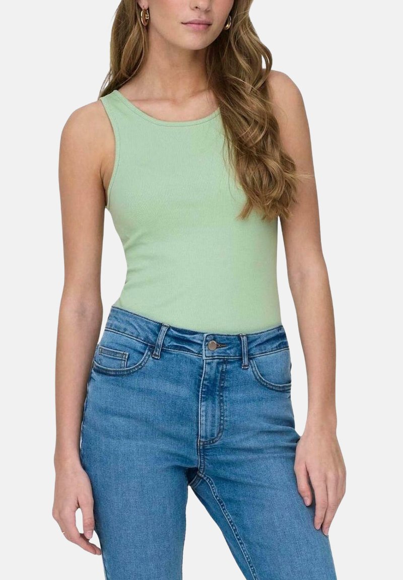 Top de tirantes acanalado verde claro con escote redondo, combinado con jeans de mezclilla azul de cintura alta que cuentan con bolsillos frontales y cierre de botón.