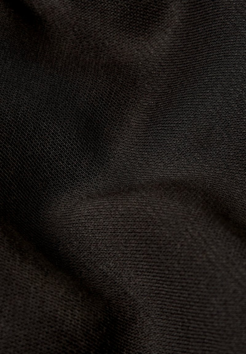 Tessuto nero lavorato a maglia con una texture liscia, che mostra una trama fine e leggermente elastica. La superficie è priva di motivi o decorazioni.