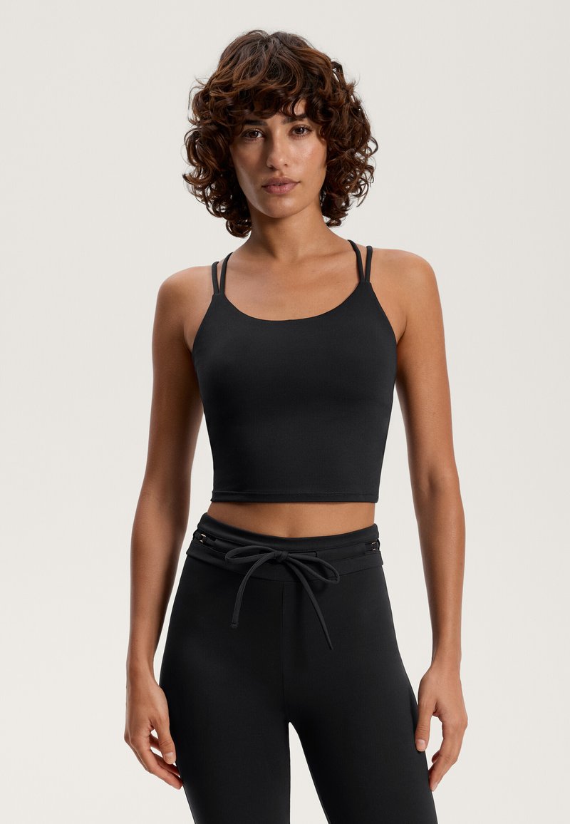 Čierny skrátený top bez rukávov s tenkými nastaviteľnými ramienkami a hladkou, elastickou textúrou, kombinovaný s čiernymi nohavicami s vysokým pásom a s možnosťou stiahnutia pomocou šnúrky.