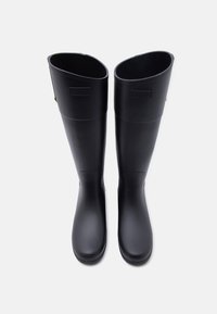 Ζευγάρι ψηλές μαύρες λαστιχένιες γαλότσες Hunter, εμφανιζόμενες από πάνω σε λευκό φόντο.