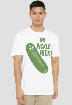 Young man wearing white T-shirt with a green cartoon pickle and the text “I'M PICKLE RICK!” on front, standing against gray background.