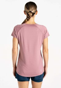 Camiseta deportiva de manga corta en rosa claro, con un tejido texturizado y dobladillo redondeado, combinada con pantalones cortos azul oscuro.