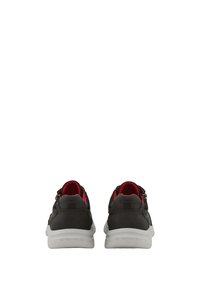 Baskets de sport noires avec une tige lisse, des accents rouges et une semelle blanche. Elles sont dotées d'une fermeture éclair et de détails texturés à l'arrière.