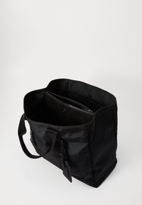 Czarna materiałowa torba na ramię z dwiema mocnymi uchwytami, zapinaną na zamek przegrodą wewnętrzną i gładką teksturą. Brak widocznych wzorów i detali metalowych.