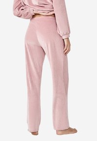 Jasnoróżowe spodnie sztruksowe o prostym kroju i miękkiej fakturze. Cechy to kieszenie boczne oraz subtelny wzór prążków.