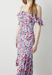 Robe maxi florale avec un fond bleu clair, ornée de fleurs rouges et bleues, des manches volantées hors des épaules et un corsage ajusté avec des fronces.