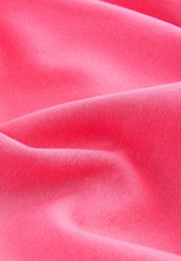 Minkštas rožinis audinys su lygiu paviršiumi, rodantis subtilias raukšles ir bangų raštus, atspindintis šviesą su šiek tiek sodriu atspalviu.