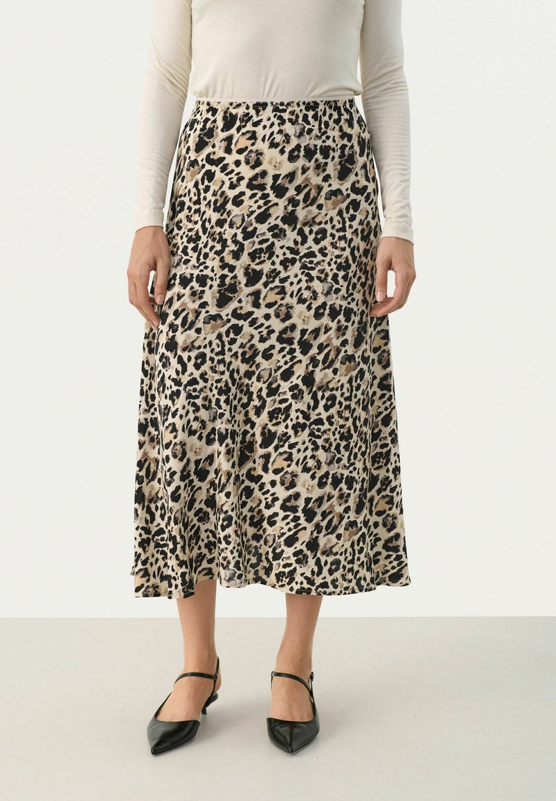 Leopardmönstrad midikjol i beige och svart, med elastisk midja och flödande silhuett. Matchas med svarta spetsiga ballerinas.