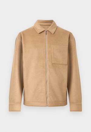 Tan fleece jacket with a front zip closure, pointed collar, and a single chest pocket. Features a relaxed fit and flat seams.
