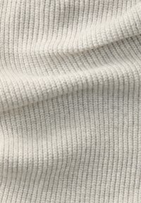 Ljust grått stickat tyg med fin ribbtextur. Mjuk, varm känsla med jämnt fördelade vertikala linjer och subtil färgvariation.