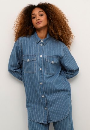 Blue denim long-sleeve shirt with white vertical stripes, two chest pockets, and silver snap buttons, featuring a relaxed fit and classic collar.