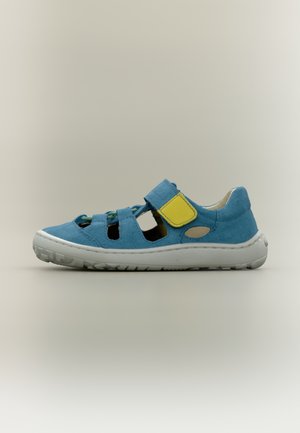 Chaussure en daim bleu clair au design ouvert, avec une bride jaune et des lacets verts, semelle en caoutchouc blanc et trous de ventilation sur les côtés.
