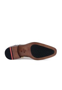 Semelle de chaussure en cuir brun avec une texture en caoutchouc noir, présentant une bande d'accent rouge et un logo en relief. Détails de couture distincts.