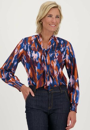 Multikleurige blouse met een abstract patroon in blauwe, oranje en roze tinten, met een striknek, lange mouwen en geplooide manchetten.