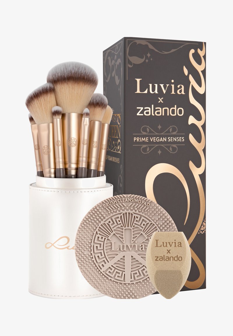 Set di pennelli per trucco con otto pennelli con manici in tonalità oro. Include un contenitore tondo bianco, un pad di pulizia in silicone e una spugna, tutti con design eleganti.