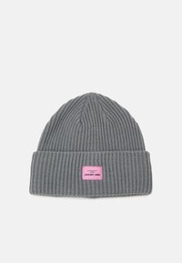 Gorro de punto gris con canalé vertical. Presenta un puño doblado y una etiqueta rectangular rosa con texto. Textura suave, diseño casual.