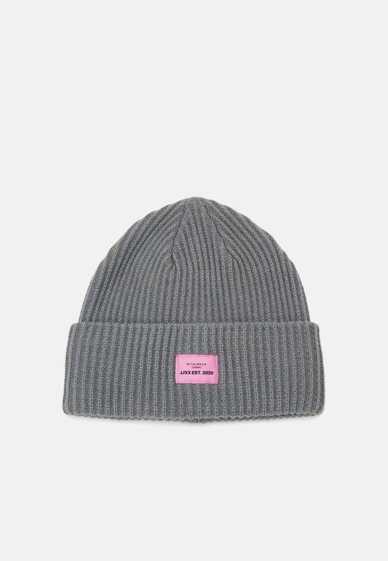 Gorro de punto gris con canalé vertical. Presenta un puño doblado y una etiqueta rectangular rosa con texto. Textura suave, diseño casual.