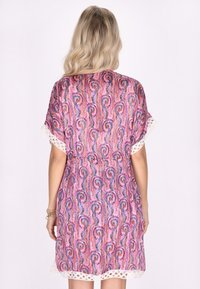 Rosa mönstrad klänning med paisleymönster, korta ärmar och vit spetsdetalj vid fållen. Lätt tyg med en avslappnad passform.
