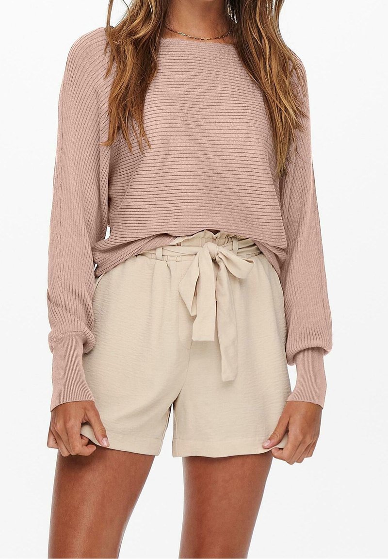 Top de manga larga de color rosa empolvado con canalé, combinado con pantalones cortos de cintura alta de color crema que cuentan con un cinturón atado y una tela suave y texturizada.