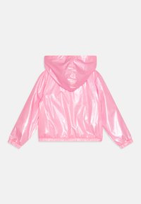 Casaco de chuva rosa e brilhante com capuz, punhos elásticos e bainha. Textura suave com um acabamento ligeiramente reflexivo. Design casual.