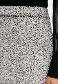 Textured grey skirt featuring a speckled pattern with brown accents, a solid waistband, and a small silver logo detail on the front.