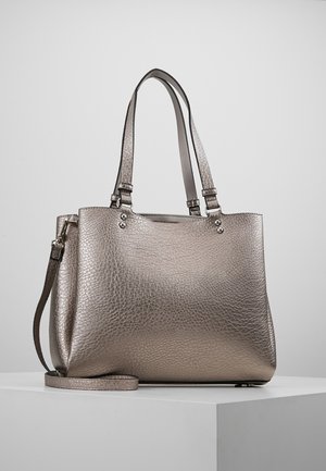 Metallic strukturierte Lederhandtasche mit doppelten Schulterriemen und abnehmbarem langen Riemen, auf einem weißen Sockel vor einfachem Hintergrund platziert.