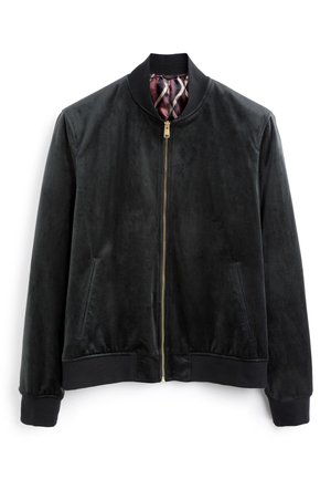 Czarna kurtka ze złotym zamkiem częściowo otwarta, odsłaniająca bordową i beżową podszewkę z geometrycznym wzorem w środku.