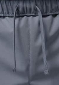 Szare szorty wykonane z gładkiego, lekkiego materiału, z elastycznym pasem i regulowanym sznurkiem dla dopasowania. Prosty design bez wzorów.