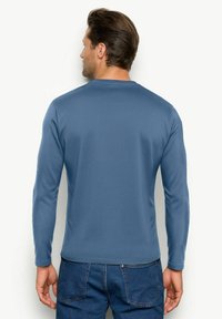 Maglietta a maniche lunghe con colletto rotondo di colore blu uniforme, realizzata in tessuto morbido. Include una vestibilità slim e una texture liscia, senza fantasie o decorazioni.