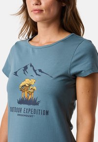 Lyhythihainen sininen puuvillapaita, jossa on graafinen kuva sienistä ja vuorista sekä teksti "Outdoor Expedition Swedemount" alla.