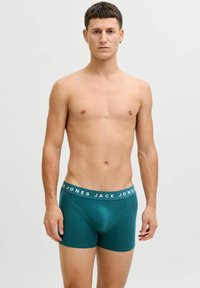 Miesten bokseritrikoot syvätealissa, valkoisella brändätyllä elastisella vyötärönauha. Silkkinen kangas, tiukka istuvuus ja ilman näkyviä kuvioita.