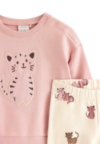 Lyserød bomulds sweatshirts med broderet katte design; cremefarvede bukser med et mønster af små katteillustrationer.