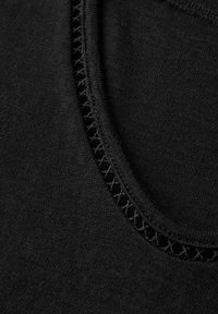 Černá látka zblízka se zaobleným výstřihem s krajkovým detailem, hladkou texturou a jednotnou, tmavou barvou po celé ploše.