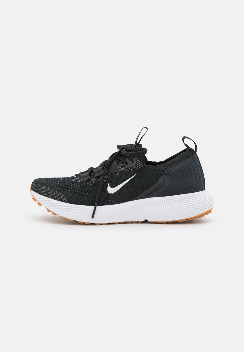 Chaussures de sport noires avec une empeigne en maille texturée, une semelle intermédiaire blanche et une semelle extérieure en caoutchouc orange. Dotées d'un système de laçage et d'une languette de tirage au talon.