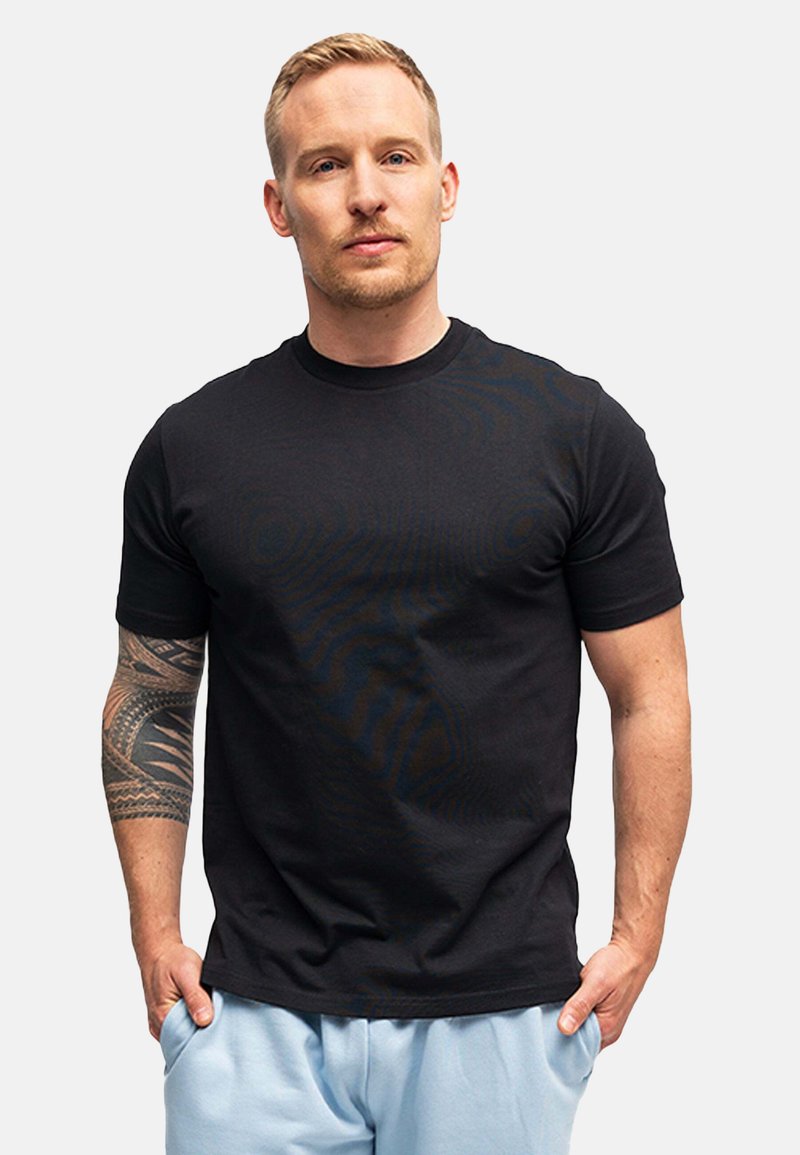 T-shirt nera in cotone con maniche corte, scollo rotondo e una consistenza liscia. Presenta un design aderente e un dettaglio logo discreto.