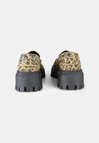 Scarpe con stampa leopardata, superficie testurizzata, suola nera spessa e battistrada pronunciato. Presentano una punta rotonda e un tacco leggermente rialzato.