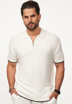 Weißes gestricktes Polohemd mit Reißverschlusskragen, kurzen Ärmeln und schwarz eingefassten Bündchen, mit einem strukturierten Muster über das gesamte Hemd.