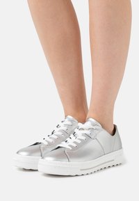 Sølvfarvede metalliske sneakers med hvide snørebånd, afrundet tå, struktureret sål og minimalistisk design. Overdelen har glat læder og syning Detaljer.