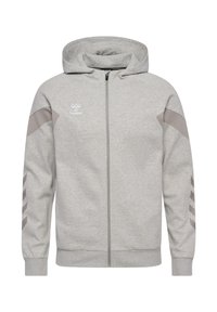 Felpa grigia con zip realizzata in tessuto morbido, dotata di cappuccio, con dettagli grigi chiari e un motivo a tre righe sulle maniche. Logo Hummel sul petto.