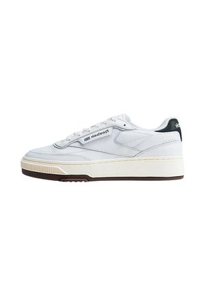Sneaker Reebok bianco low-top con tallone nero, suola beige e logo sul lato e sul tallone su sfondo bianco.