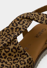 Σανδάλι με λεοπάρ σχέδιο που διαθέτει πάνω μέρος από στριφτό ύφασμα, μαλακή υφή και μπεζ εσωτερικό με ελαφρώς καμπυλωμένη φτέρνα.