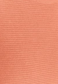 Tissu tricoté de couleur corail douce, présentant une finition texturée avec des côtes horizontales et une apparence légère et respirante.
