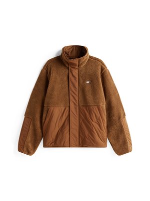 Chaqueta de forro polar marrón con cuello alto, que presenta un diseño de panel marrón liso, cremallera frontal y un pequeño logo en el pecho.