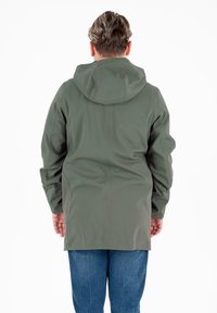 Parka impermeabile verde oliva con cappuccio, design senza cuciture e polsini elasticizzati, indossata sopra jeans blu, che mostra una vestibilità rilassata e vista posteriore.