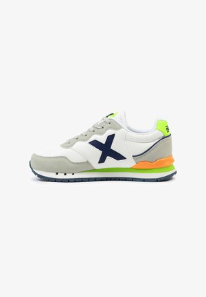 Zapatilla con parte superior de cuero blanco y ante gris, logo en azul marino, acentos en verde lima y naranja, suela texturizada y cordones grises.