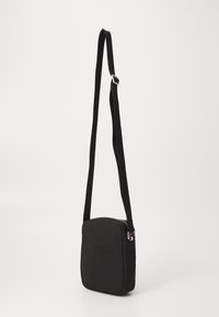 Černá crossbody taška obdélníkového tvaru vyrobená z odolného materiálu, s zipovým uzávěrem a nastavitelným popruhem. Jednoduchý design.