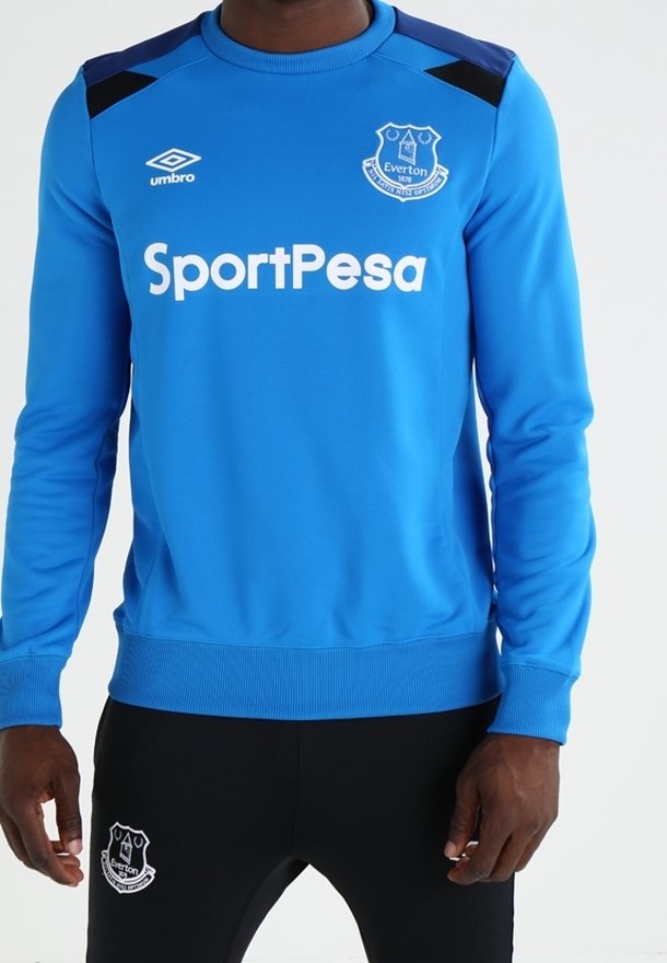 Blå långärmad sweatshirt med svarta axelaccent, med "SportPesa"-logotyp och Everton-emblem på framsidan, ribbstickade muddar och fåll.