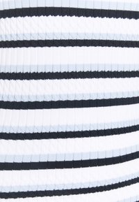 Bílá látka s horizontálními pruhy v alternující světle modré a tmavě námořnické barvě a žebrovanou, kabelkovou texturou.